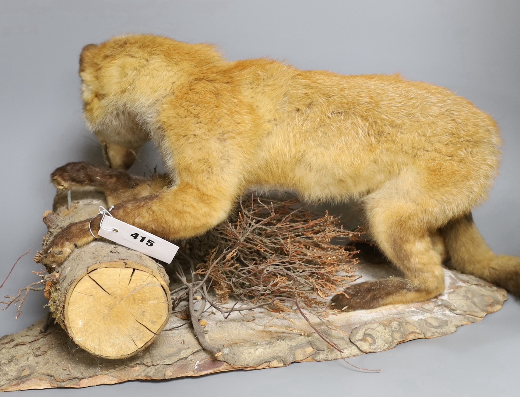 A taxidermy fox on a wooden base perched on log